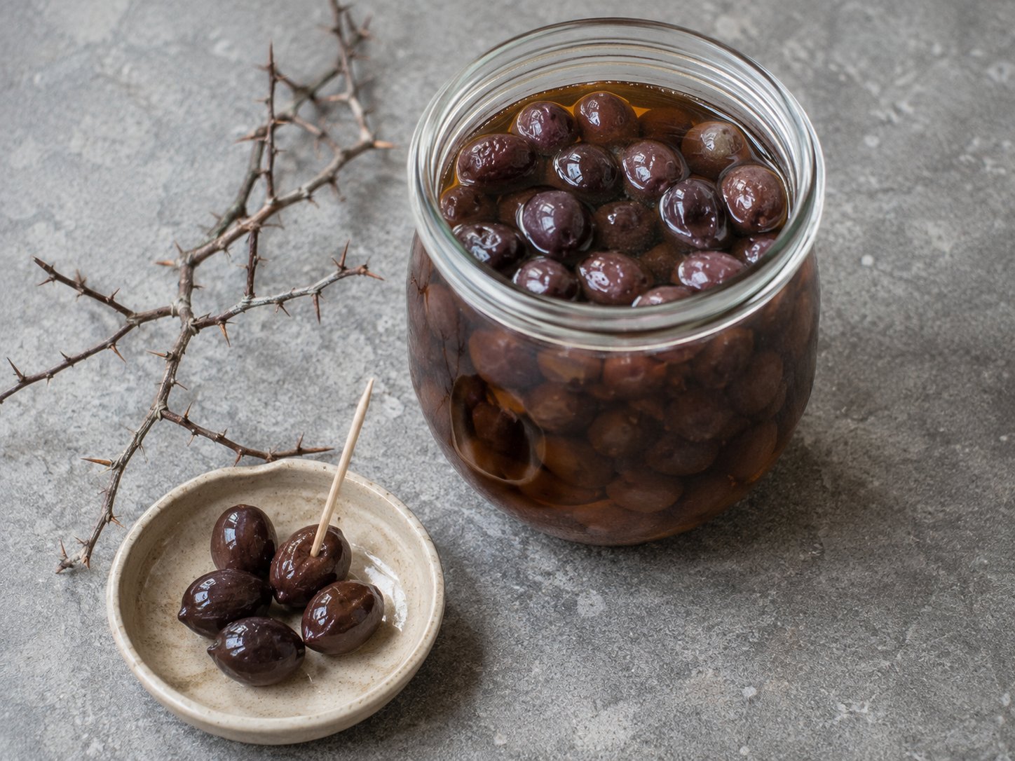 Prunelles lactofermentées dans un bol en grès, brun-violet foncé, rappelant des olives noires